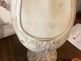a white urn sitting on top of a table next to a pair of scissors