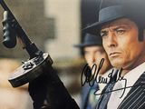l'image d'un homme en costume et chapeau, tenant un pistolet
