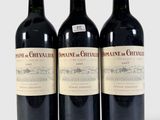 trois bouteilles de vin rouge posées l'une à côté de l'autre sur une surface blanche