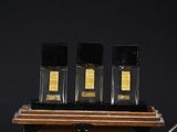 three bottles of perfume on a wooden shelf with a pen and paper