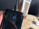 a person holding a cell phone that is connected to a charger