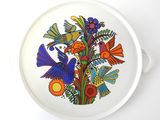 une assiette blanche décorée d'oiseaux et de fleurs colorés