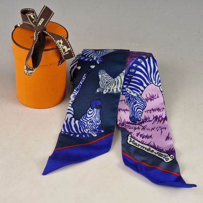 une écharpe bleue et violette avec des zèbres dessus, à côté d'un seau orange