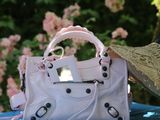 a white purse sitting on a blue table with pink flowers in the background