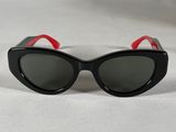 black cat eye sunglasses with red trims on a white surface