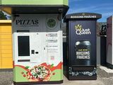 un distributeur automatique situé sur un parking, à côté d'une poubelle