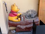 une statue de Winnie l'ourson assise sur une valise