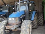 Plusieurs tracteurs bleus sont garés en rangée dans un garage