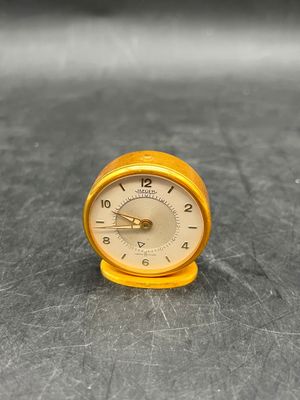 a small clock sitting on a table with a black background