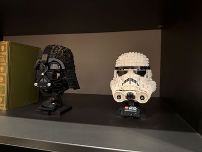 two star wars helmets on a shelf next to a book
