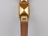 a brown leather watch strap with gold pyramids on it
