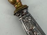 a silver spoon with a gold handle on a white table