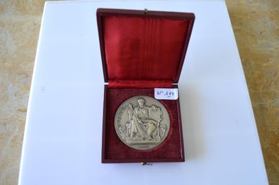 une vieille médaille d'argent dans un écrin rouge posé sur une surface blanche