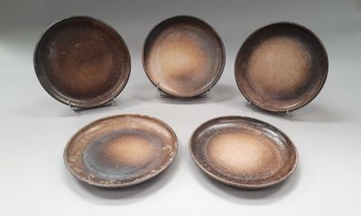 four brown plates sitting next to each other on a white surface