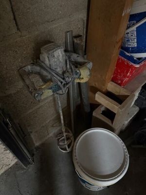 un seau de peinture posé à côté des toilettes dans une pièce