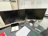two computer monitors sitting on a desk next to each other