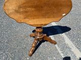 a small wooden table on a tripod with a shadow on the ground