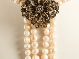 a close up of a necklace on a mannequin with pearls and a broochet