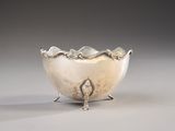 an antique silver bowl with a bird on it on a table