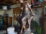 a statue of a woman sitting on a pedestal in a living room