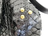 a close up of a black purse with gold buttons on it