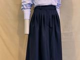 Le mannequin porte une chemise bleue et blanche et une jupe noire.