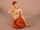 a statue of a man sitting on the ground with his hand on his head