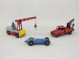 trois petites voitures et une grue posées sur une surface blanche