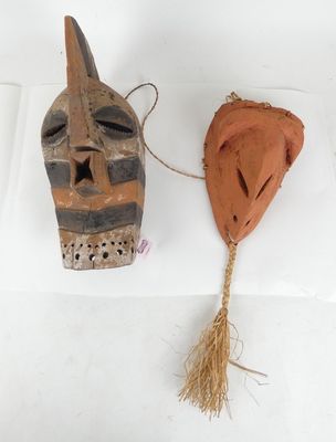 deux masques en bois posés sur une surface blanche, avec une corde