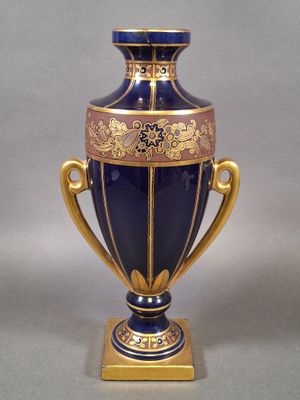 un vase bleu orné de motifs dorés, posé sur un socle