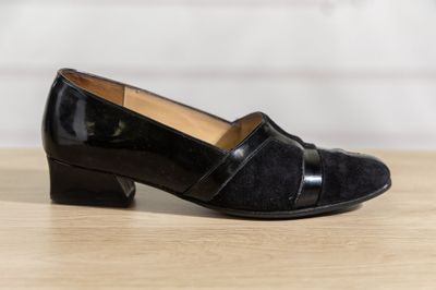 the black shoes are on a wooden table near a white wall