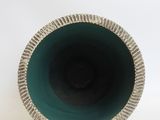 a close up of a green vase on a white surface