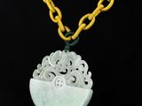un pendentif en jade blanc avec une chaîne jaune sur fond noir