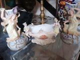three figurines sitting on a glass shelf next to a lamp