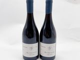 deux bouteilles de vin posées l'une à côté de l'autre sur une surface blanche
