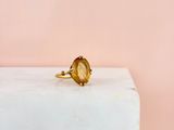 a close up of a ring with a yellow stone on top of a white block