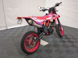 a red and white dirt bike parked in a garage