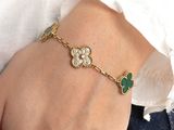 the woman is wearing a gold bracelet with green stones on it
