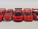 five red model cars lined up in a row on a white surface