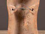 an old clay vase with writing on it sitting on a wooden table