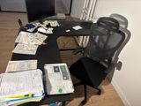 a black desk with a chair and a computer on it