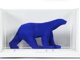 un ours polaire bleu dans une vitrine posée sur une surface blanche