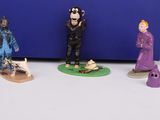three figurines of people standing in front of a blue box