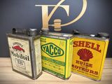 three old fashioned oil cans sitting on top of a wooden table