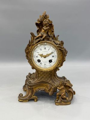 a gold clock with a statue on top of it