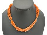 un gros plan d'un collier orné de perles orange sur un mannequin