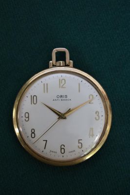 une montre de poche en or posée sur un tissu vert