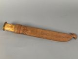 an old wooden knife with a carved handle sitting on a white surface
