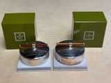 two silver bowls with chopsticks and a box on a table