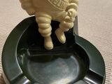a small statue of a man sitting on top of a ashtray